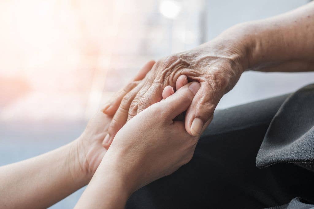 Two hands, one elderly and wrinkled, the other younger and smooth, holding each other.