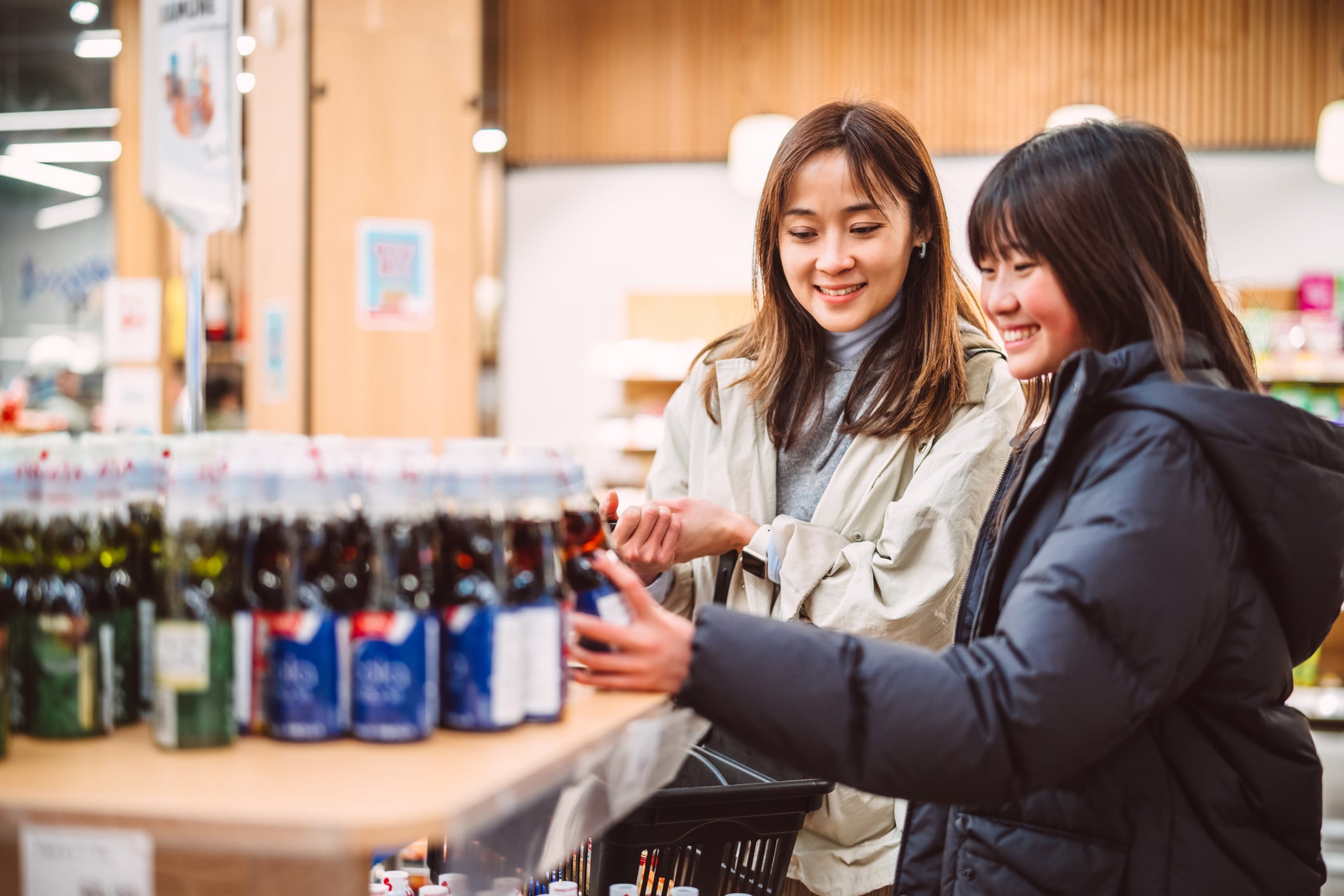Asian mom and daughter choosing drinks in supermarket