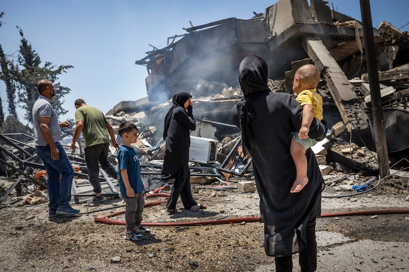 A family gathers near their destroyed home in Kfar Roummane, Lebanon, on Sunday. Photograph: David Guttenfelder/The New York Times
                      