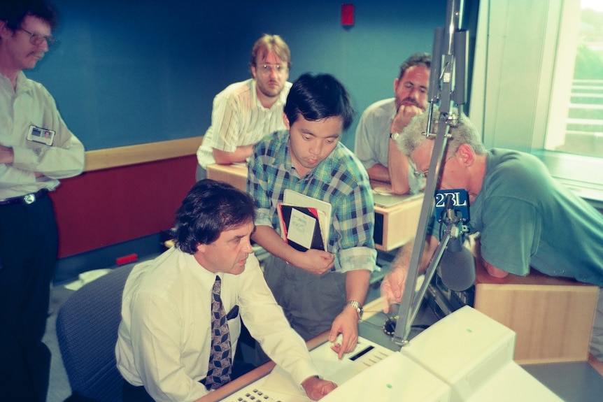 a man points to a studio control desk