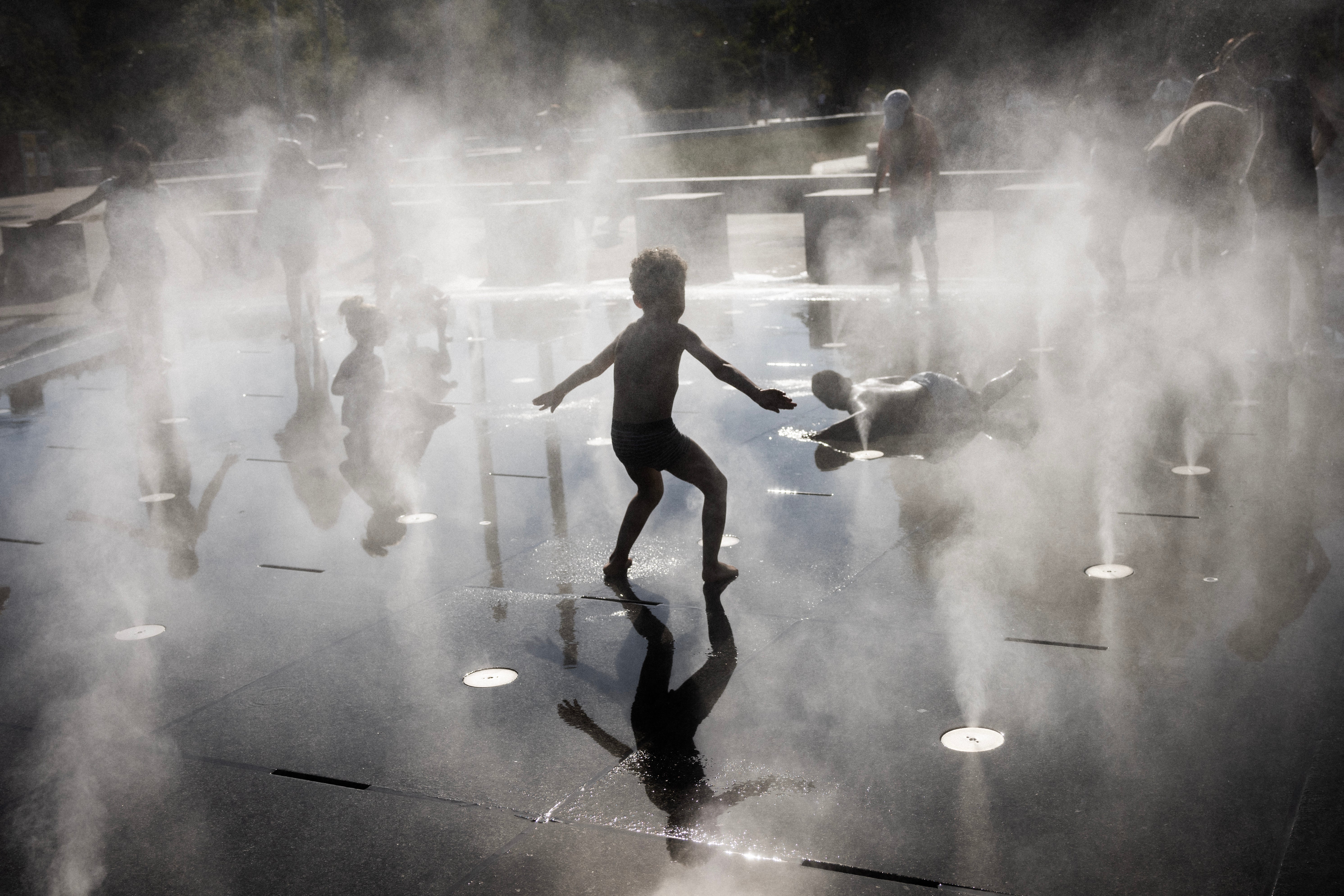 Children play in a splash pad during a heatwave in Paris on July 10, 2026.