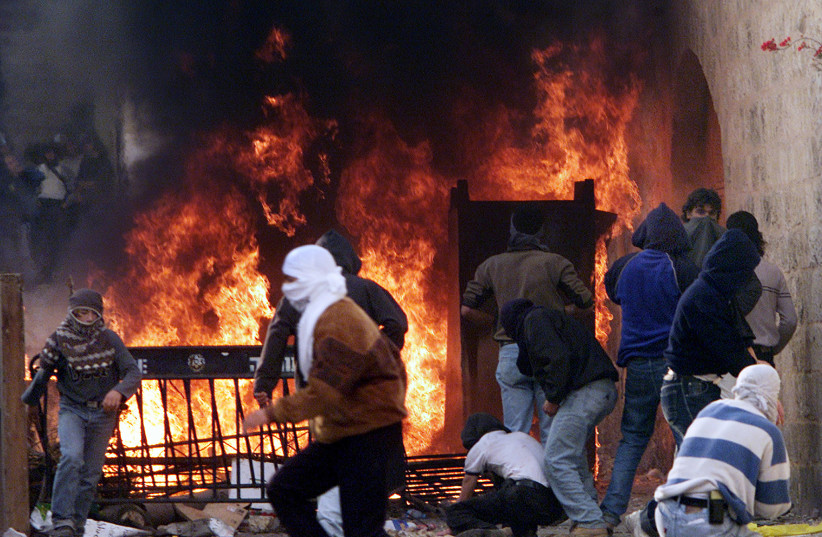 Palestinians man a burning barricade on the Via Dolorosa in Jerusalem's Old City as they fight violent clashes with Israeli Border Police following the second Friday noon prayers in the Muslim holy month of Ramadan during the Second Intifada. December 8, 2000.