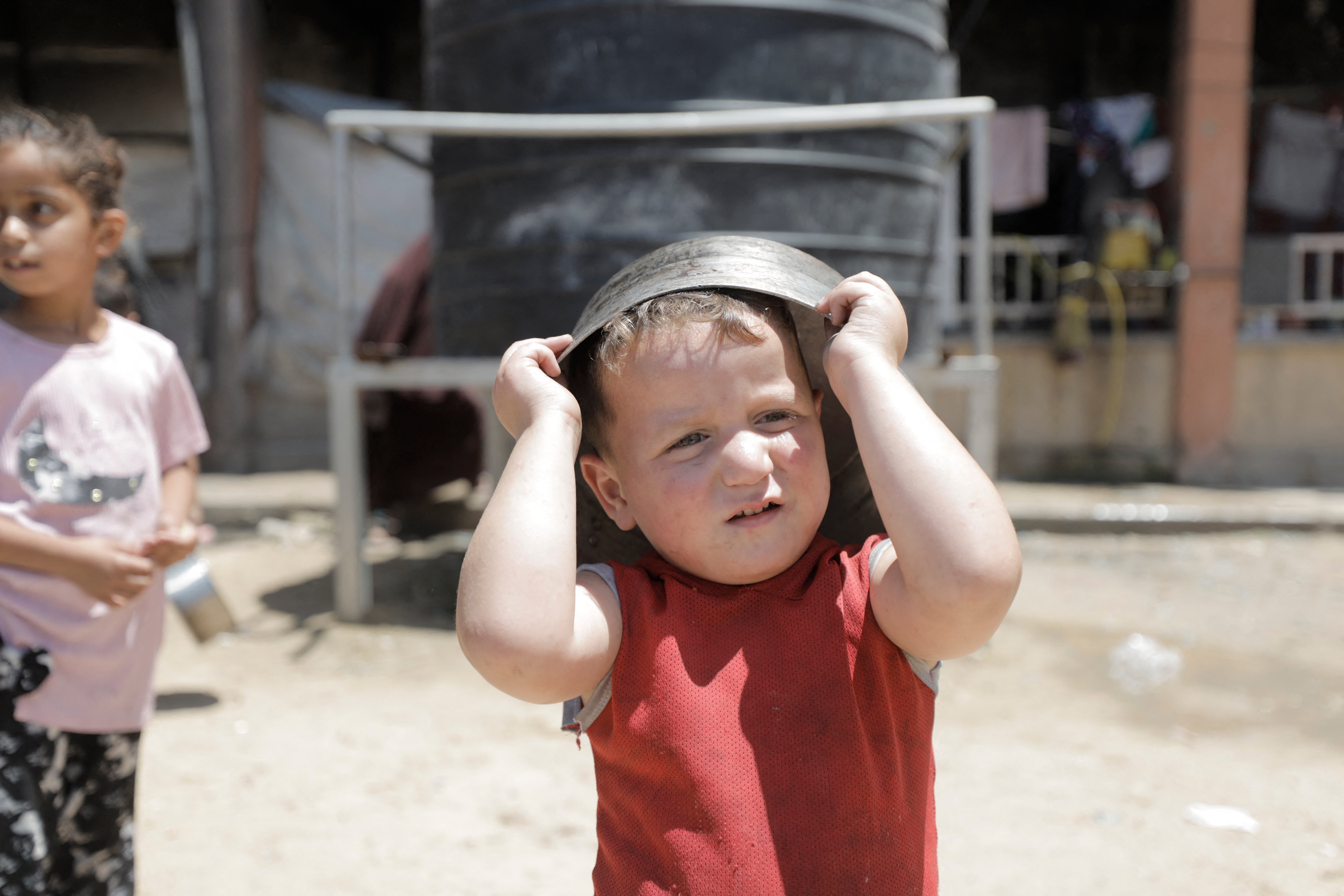 A displaced Palestinian child holds a cooking pot on his head in the grounds of al-Faluja School in Jabalia refugee camp in the northern Gaza Strip, on June 21, 2026. Over 20,000 children have been killed in Gaza.