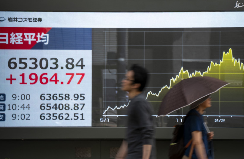 Pedestrians walk past an electronic quotation board displaying the Nikkei Stock Average on the Tokyo Stock Exchange along a street in Tokyo on May 25, 2026.