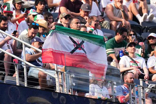 An attendees holds an Iranian flag with an "X" on it before the World Cup Group G soccer match between Iran and New Zealand in Inglewood, Calif., near Los Angeles, Monday, June 15, 2026.