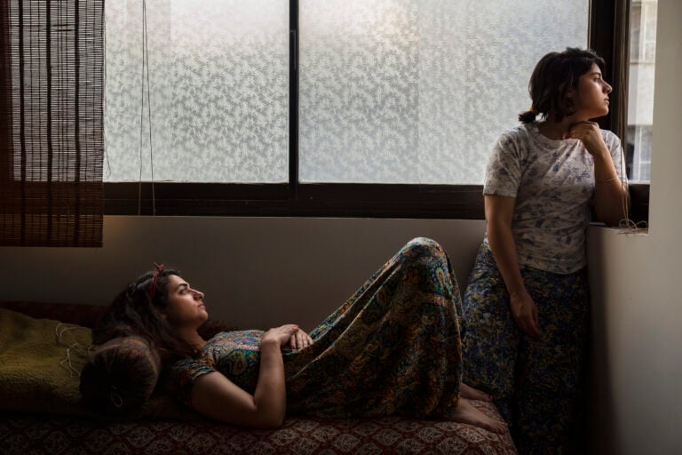 ©Parisa Azadi, Nesa e la sua amica Yasaman guardano fuori dalla finestra durante la pandemia di Covid-19 a Teheran, Iran, 9 giugno 2020