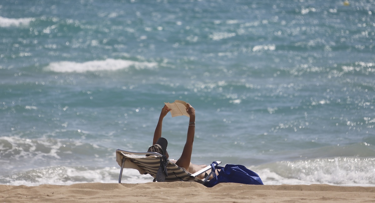 Una persona legge in spiaggia a Maiorca nel 2020 (Clara Margais/Getty Images)