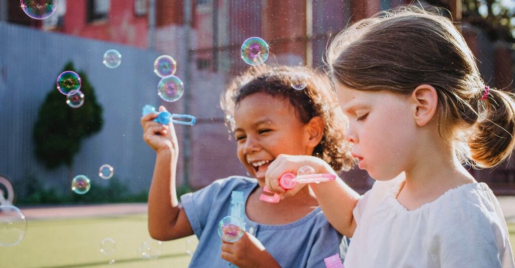 Primo piano di due bambine che soffiano le bolle di sapone