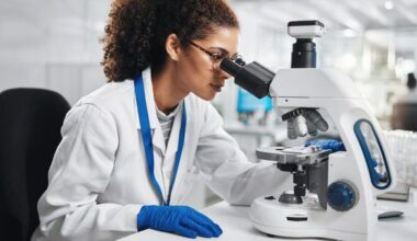 Giovane donna al microscopio durante una ricerca di laboratorio