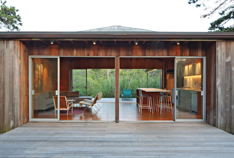 a modern wooden house with large sliding glass doors revealing an interior living space and a kitchen area