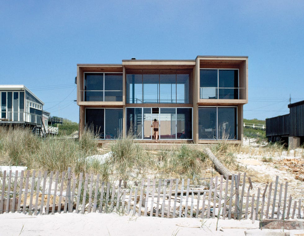 modern beach house with large windows and sandy surroundings