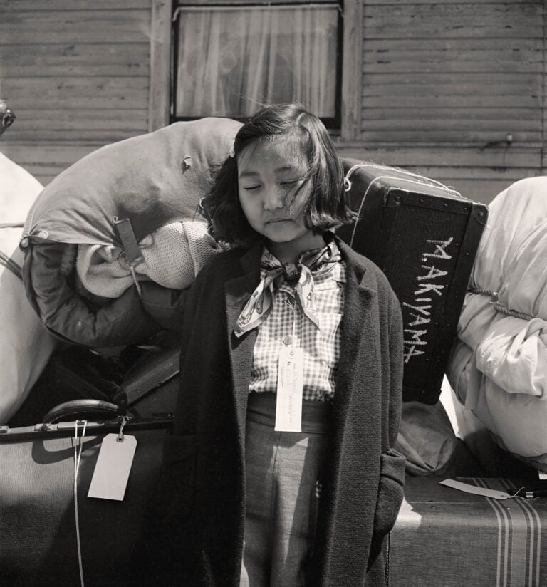 Dorothea Lange, La giovane evacuata Kimiko Kitagaki sorveglia i bagagli della famiglia prima di partire in bus, 1942. The New York Public Library - Library of Congress Prints and Photographs Division Washington