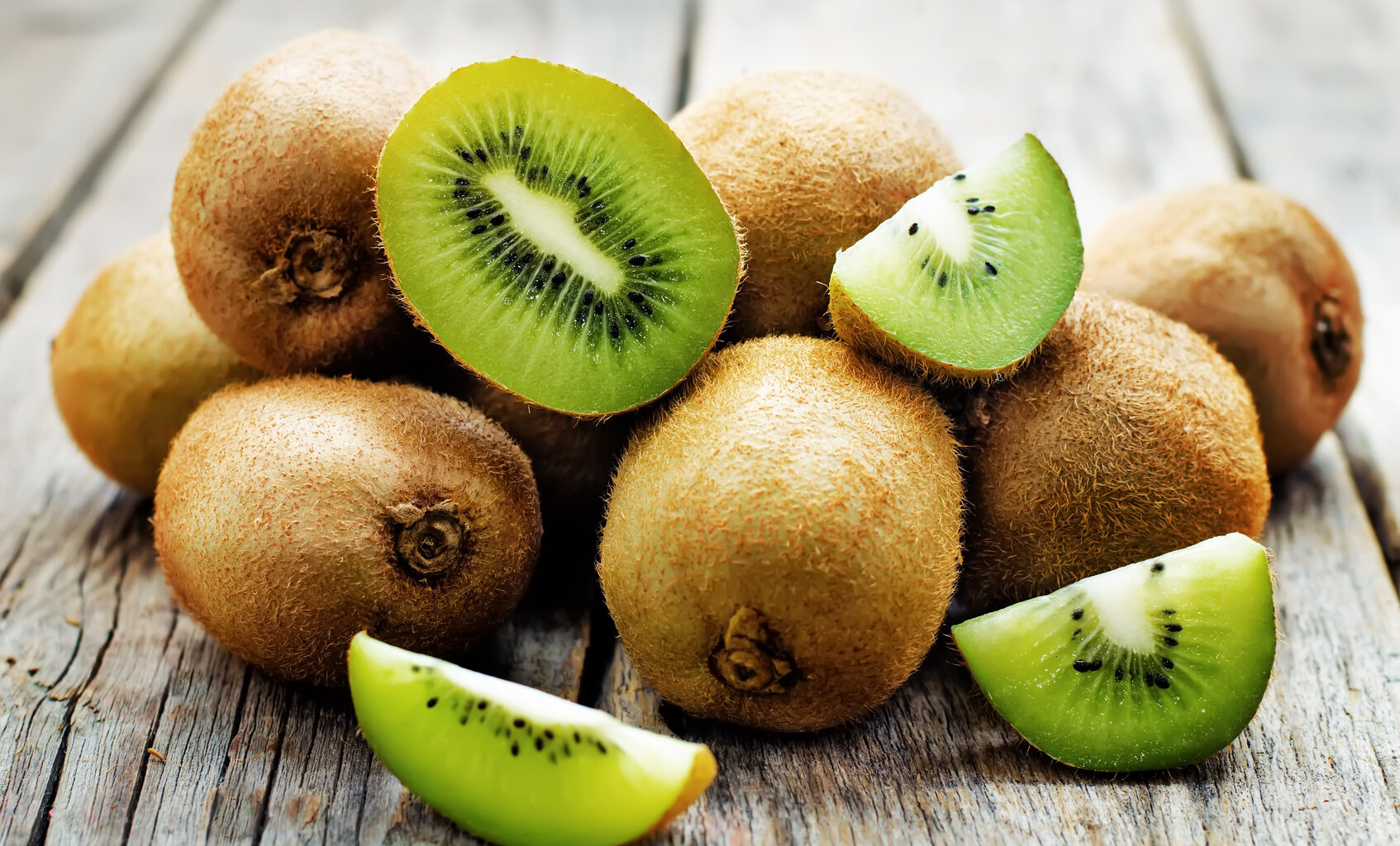 Kiwi interi e tagliati su un tavolo verde