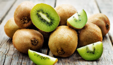 Kiwi interi e tagliati su un tavolo verde