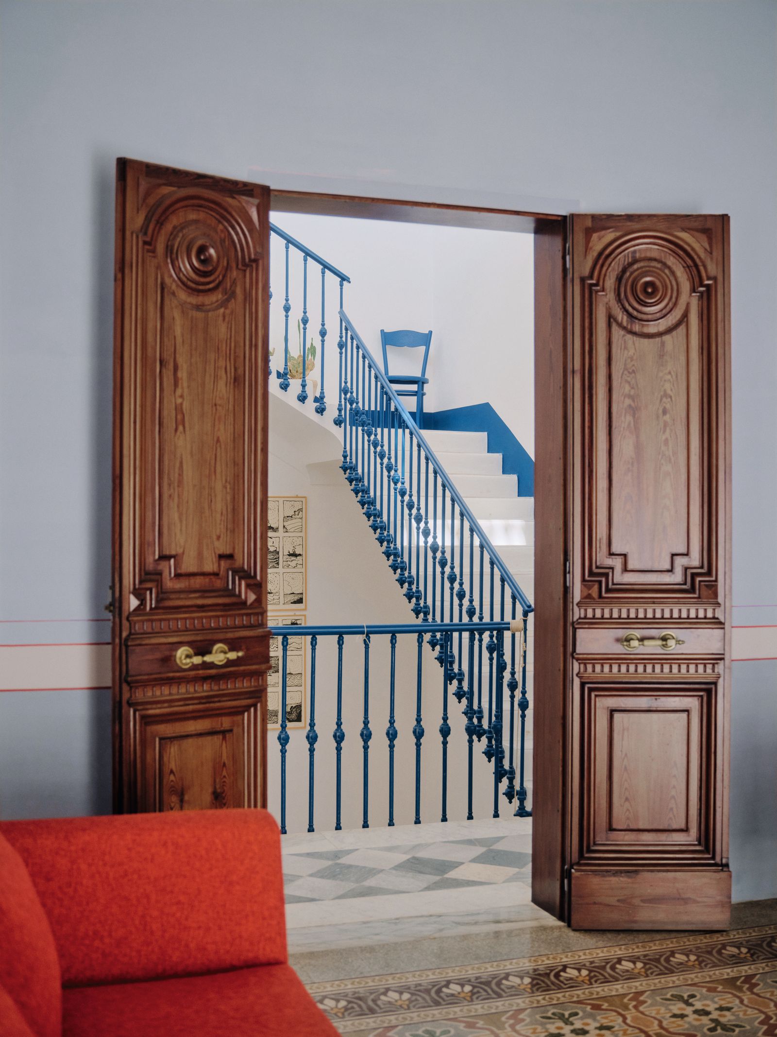 Porta in legni pavimento con cementine divano rosso scale con ringhiera blu