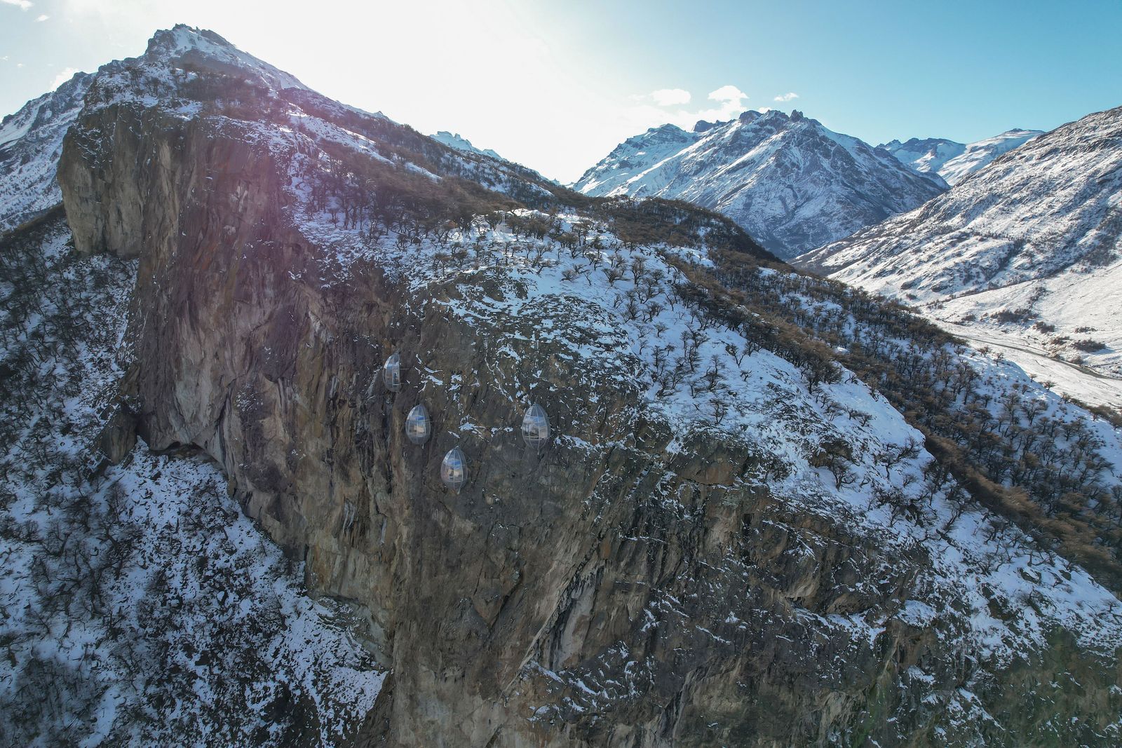 Quattro capsule trasparenti in lontananza mimetizzate da un pendio di pietra.