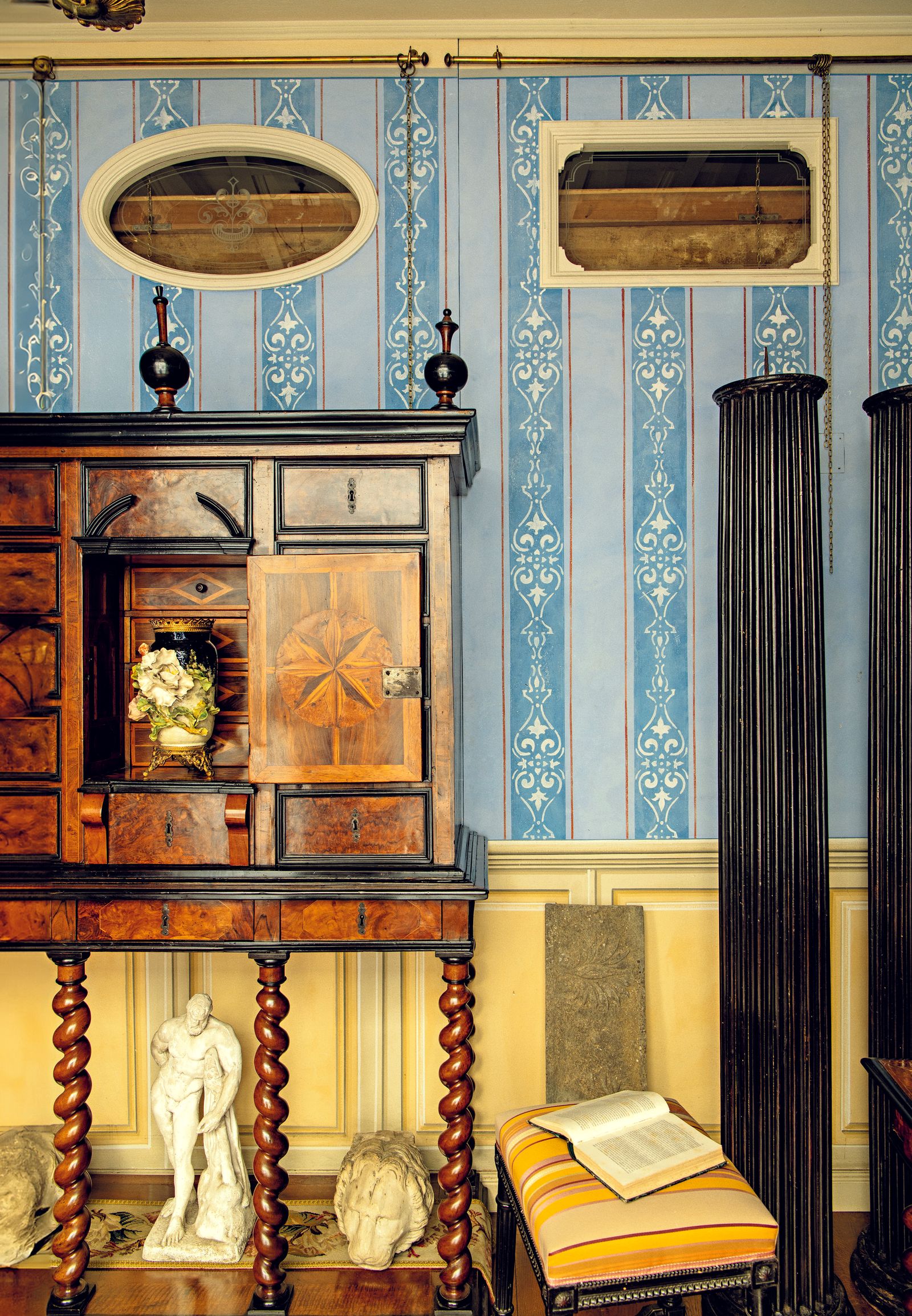 Mobile in legno antico parete con tappezzeria celeste statue pouf