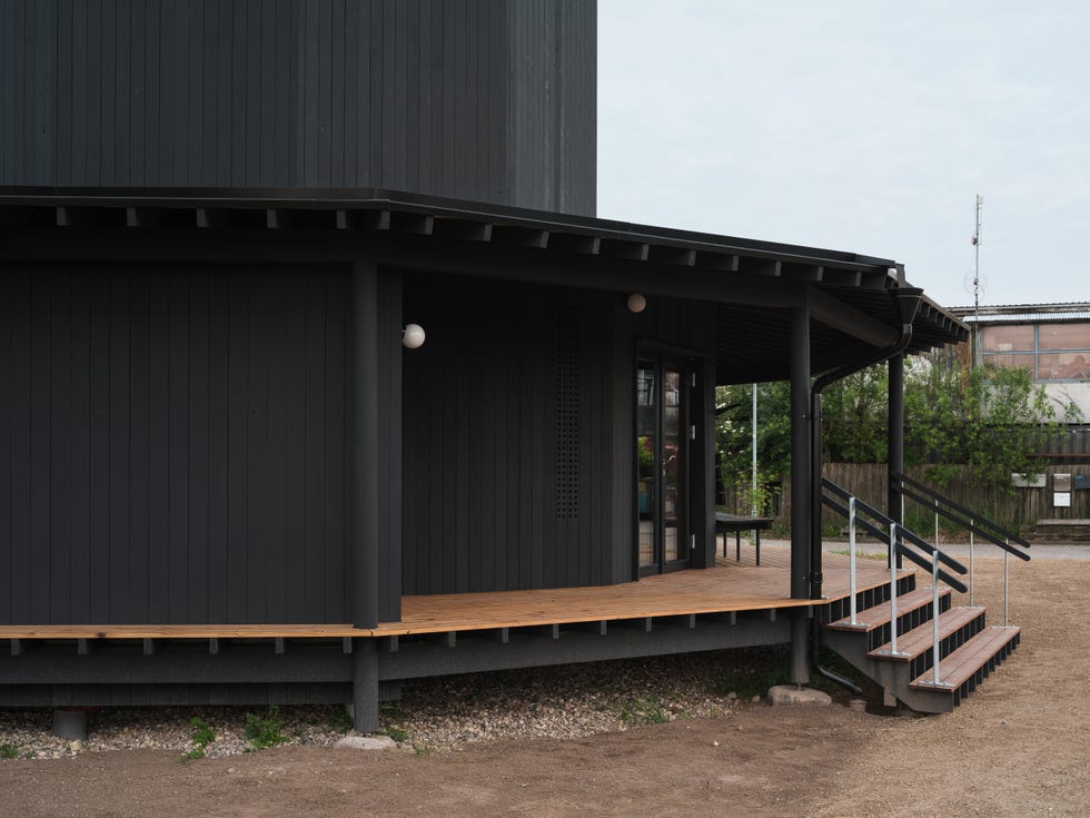 modern black structure with a wooden deck and steps