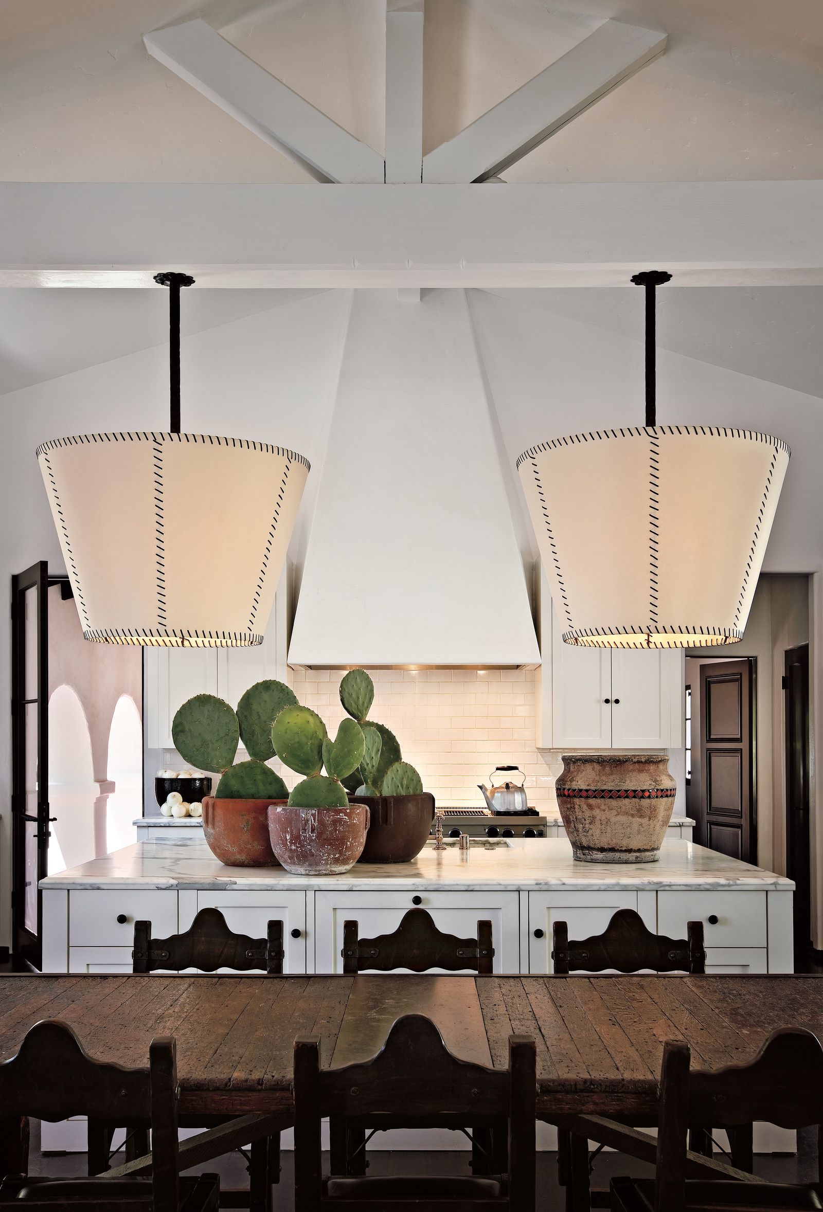 casa in stile spagnolo cucina bianca isola cucina con cactus tavolo in legno e sedie sospensioni travi a vista dipinte...