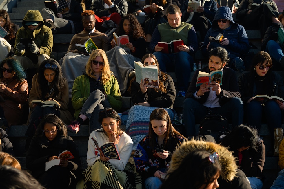 Un gruppo di persone sedute a leggere all’alba
