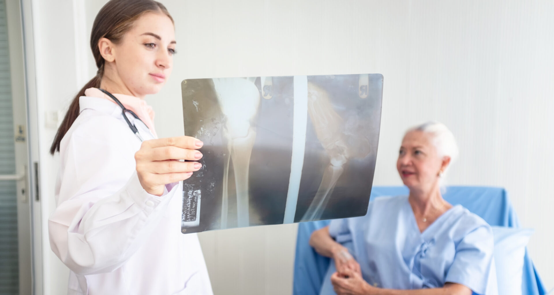 Dottoressa in piedi guarda rx e paziente su lettino