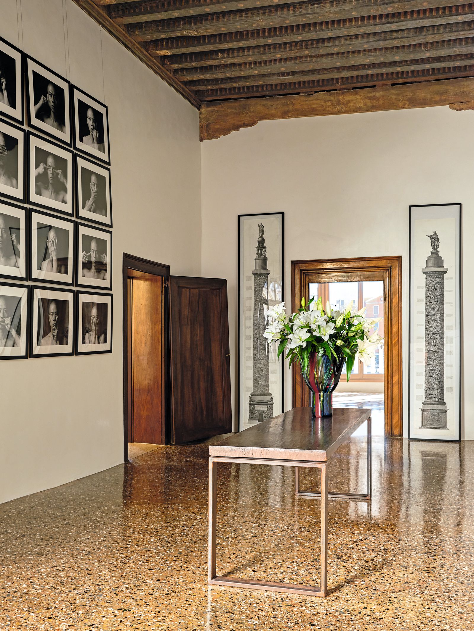 Tavolo in marmo e metallo foto in bianco e nero alla parete dipinti appoggiati alla parete soffitto a cassettoni in...