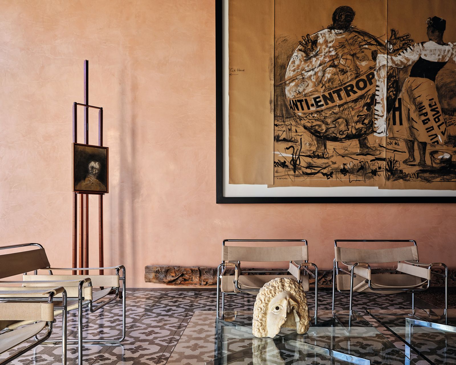 Sedie in metallo e pelle chiara tavolino in vetro dipinti pavimento bicolore testa di statua casa Venezia Giulia Foscari