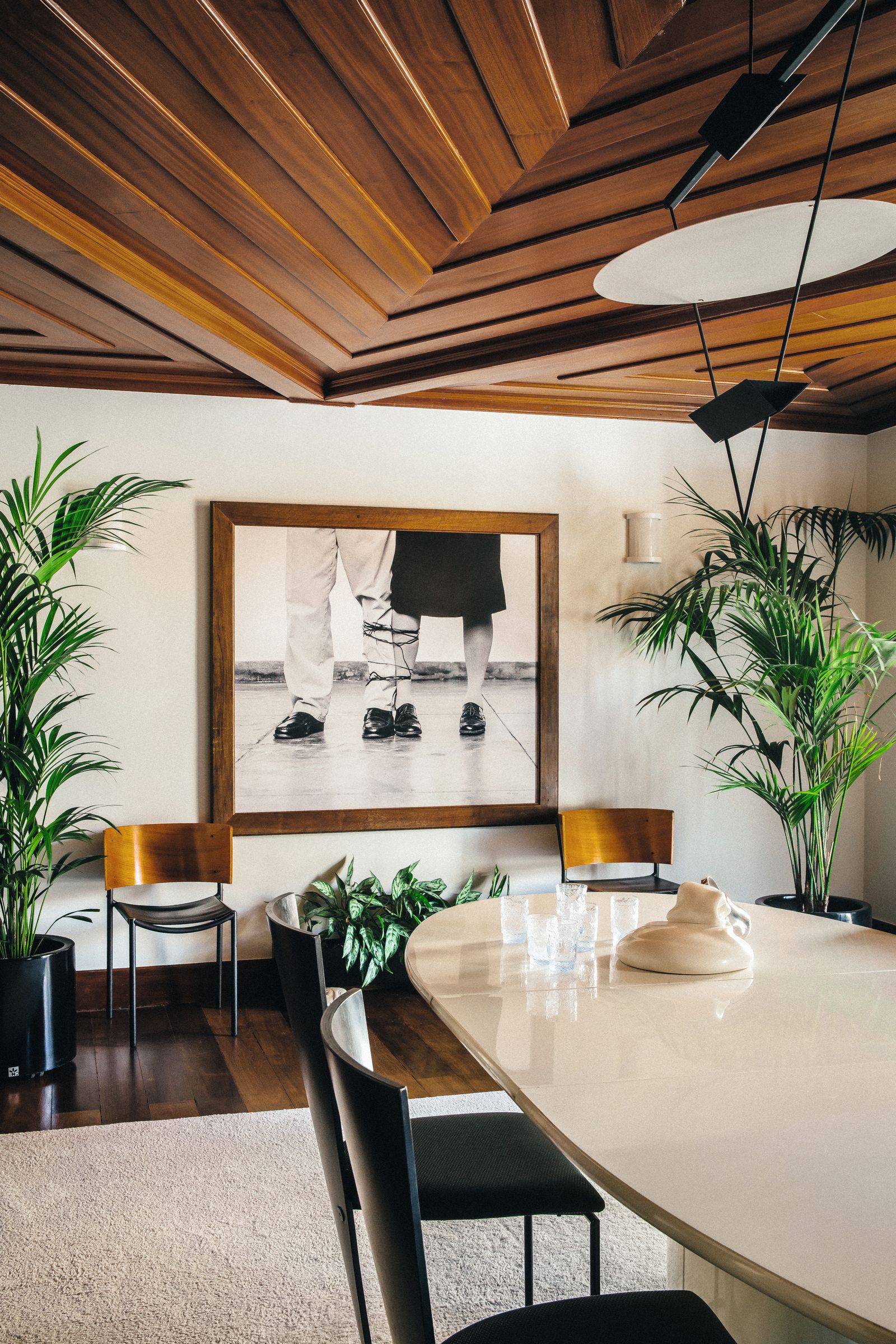 Tavolo in marmo ovale piante palme. fotografia alla parete in bianco e nero sedie soffitto in legno lampadario sedie nere