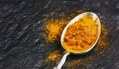 ground turmeric or curcuma in silver vintage spoon on black stone surface