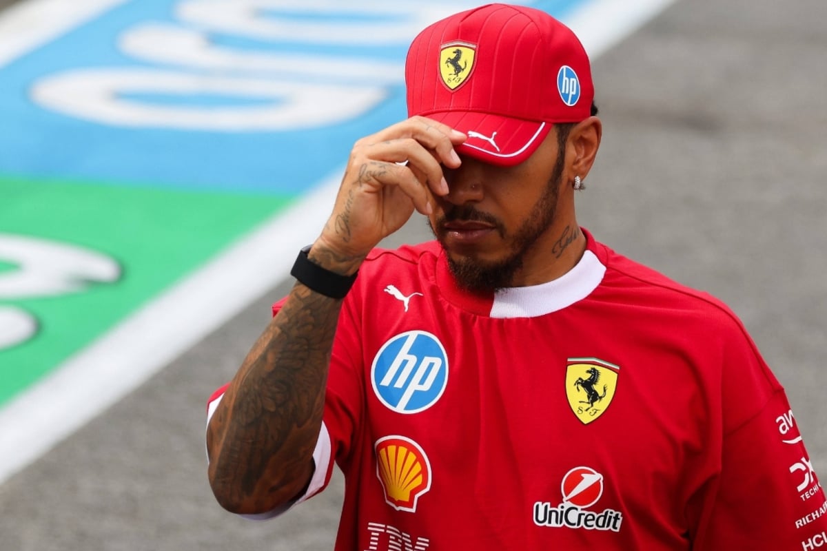 Hamilton dipping his Ferrari cap sombrely, partially hiding his face