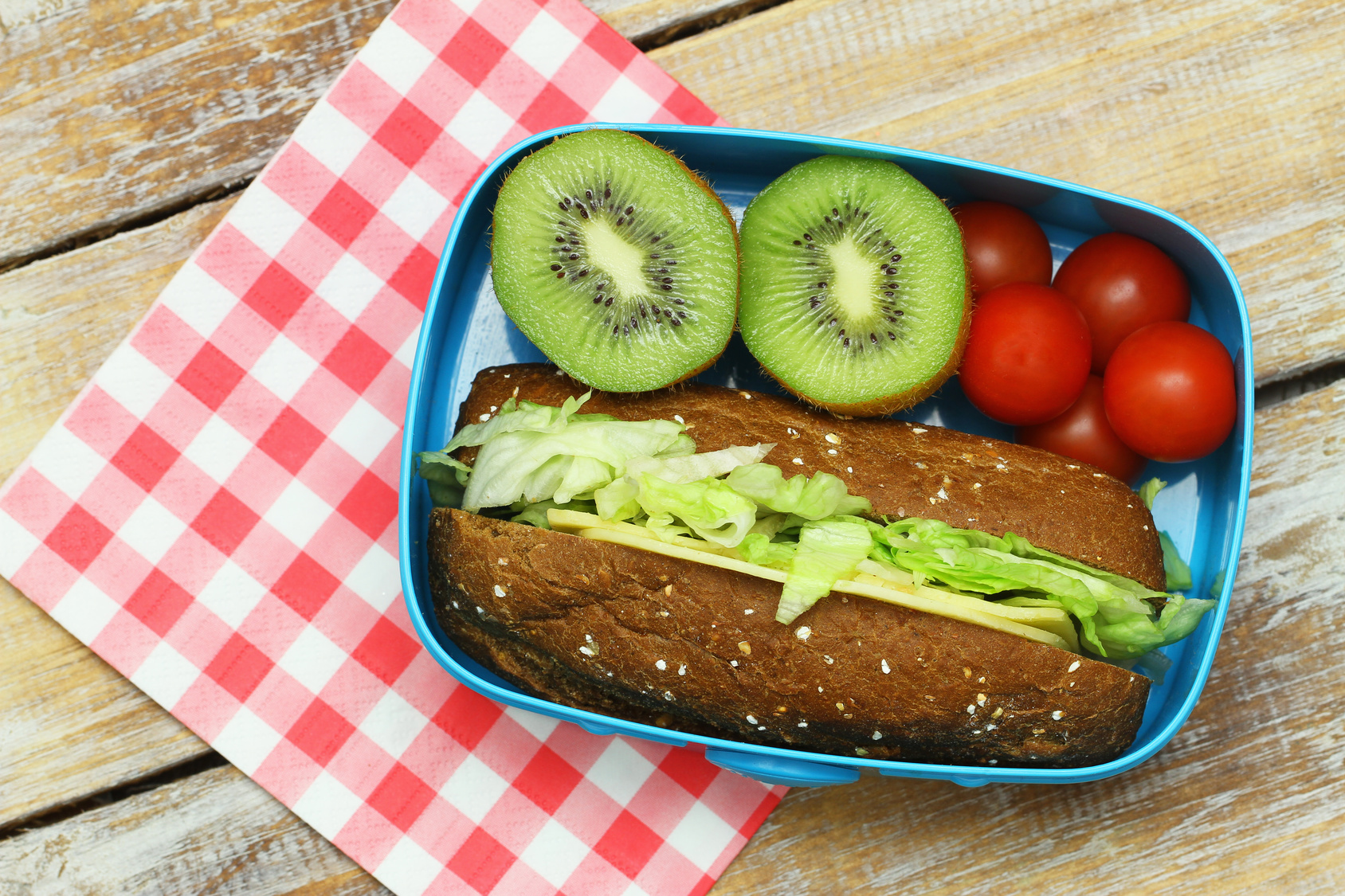 Pranzo salutare composto da involtini di formaggio bruno e lattuga, pomodorini e kiwi