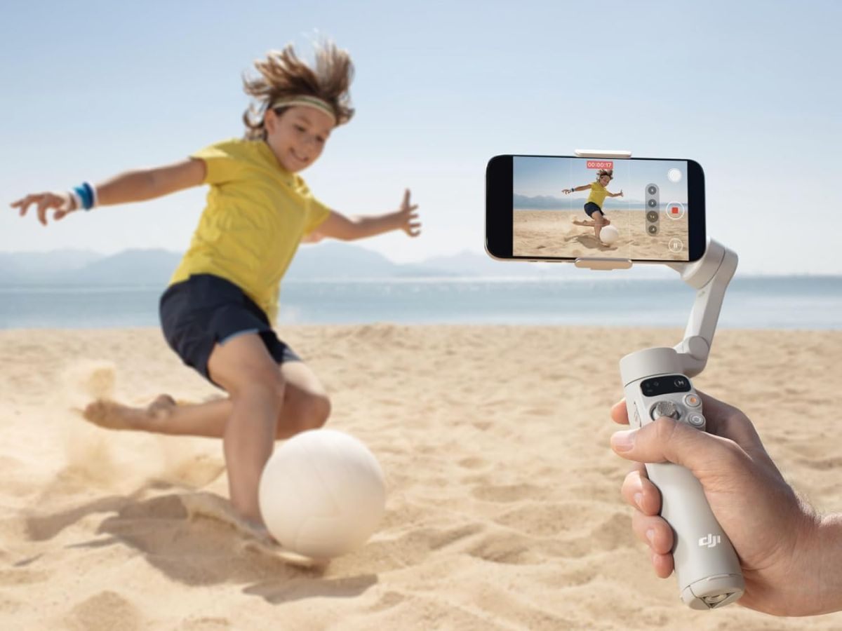 bambino che gioca a calcio sulla spiaggia ripreso da smartphone con stabilizzatore