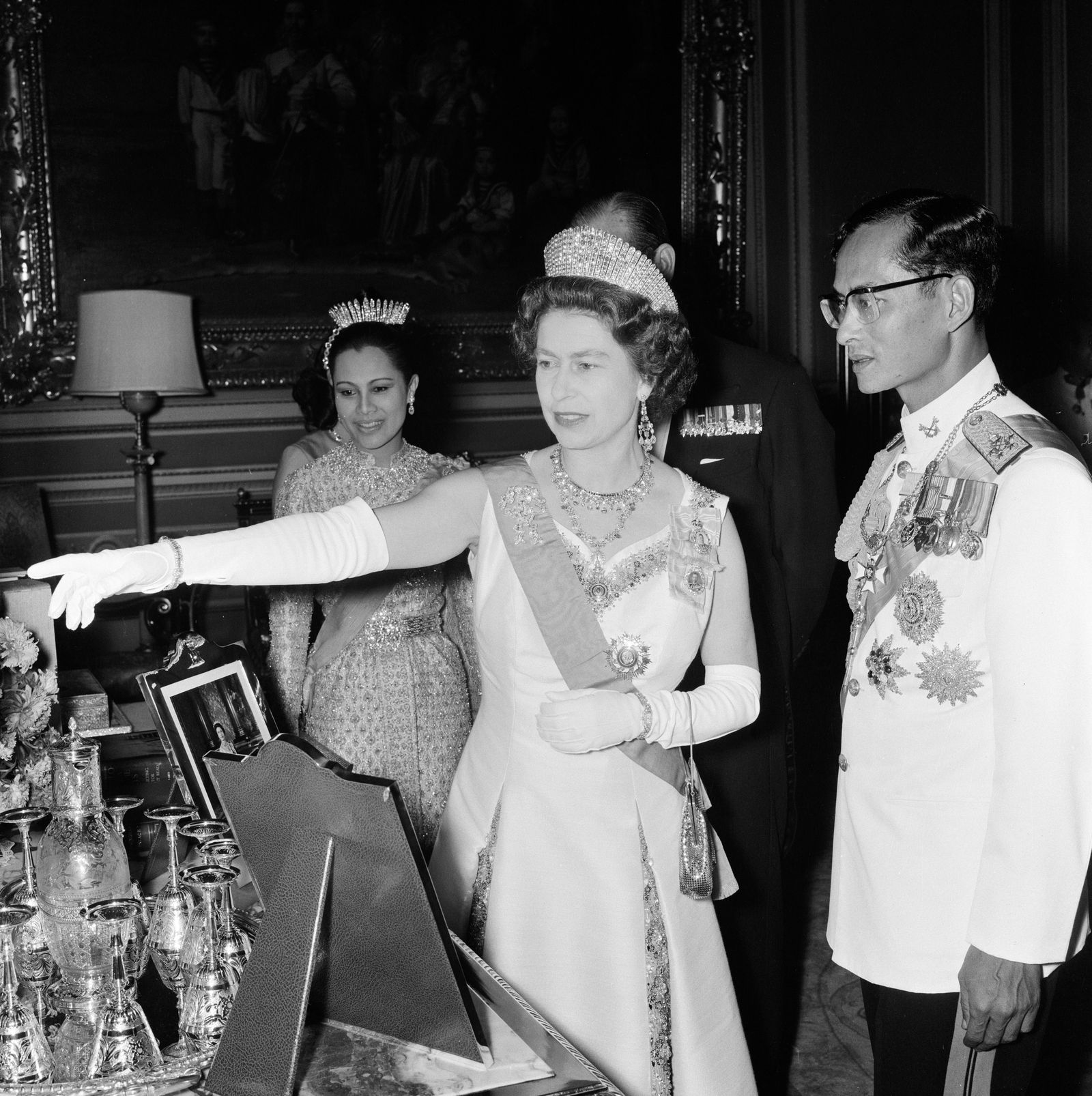La defunta regina Elisabetta con re Bhumibol nel febbraio 1972 mentre la regina Sirikit ritratta alle loro spalle...