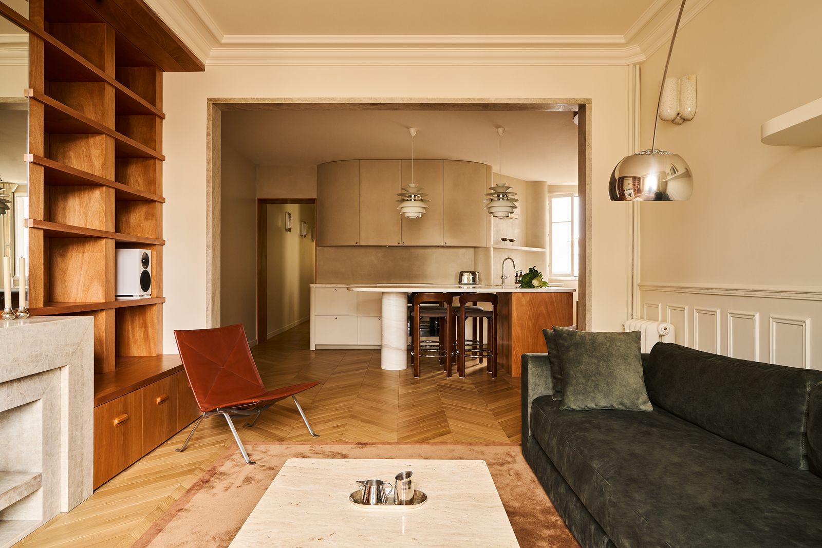 open space living e cucina pavimento in legno a spina di pesce boiserie libreria in legno divano lampada da terra