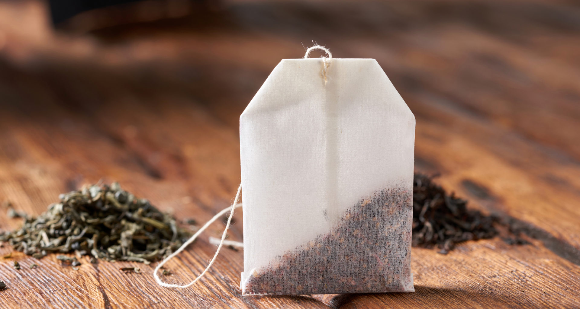 Bustina di tè o infuso con foglie di tè verde e tè nero sullo sfondo