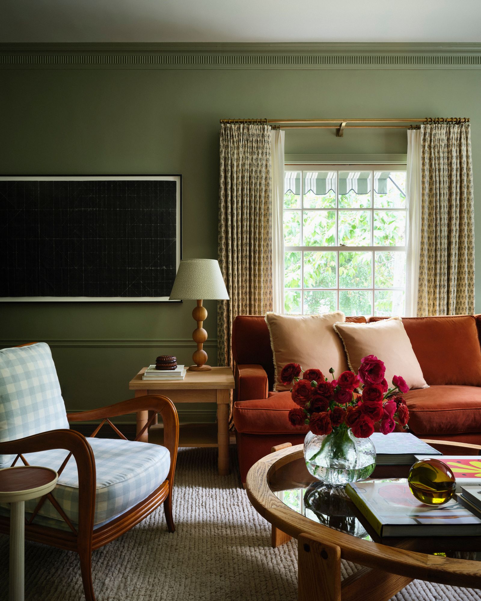 salotto divano in velluto color terracotta pareti verde salvia poltrona a quadri tavolino rotondo in legno e vetro vaso...