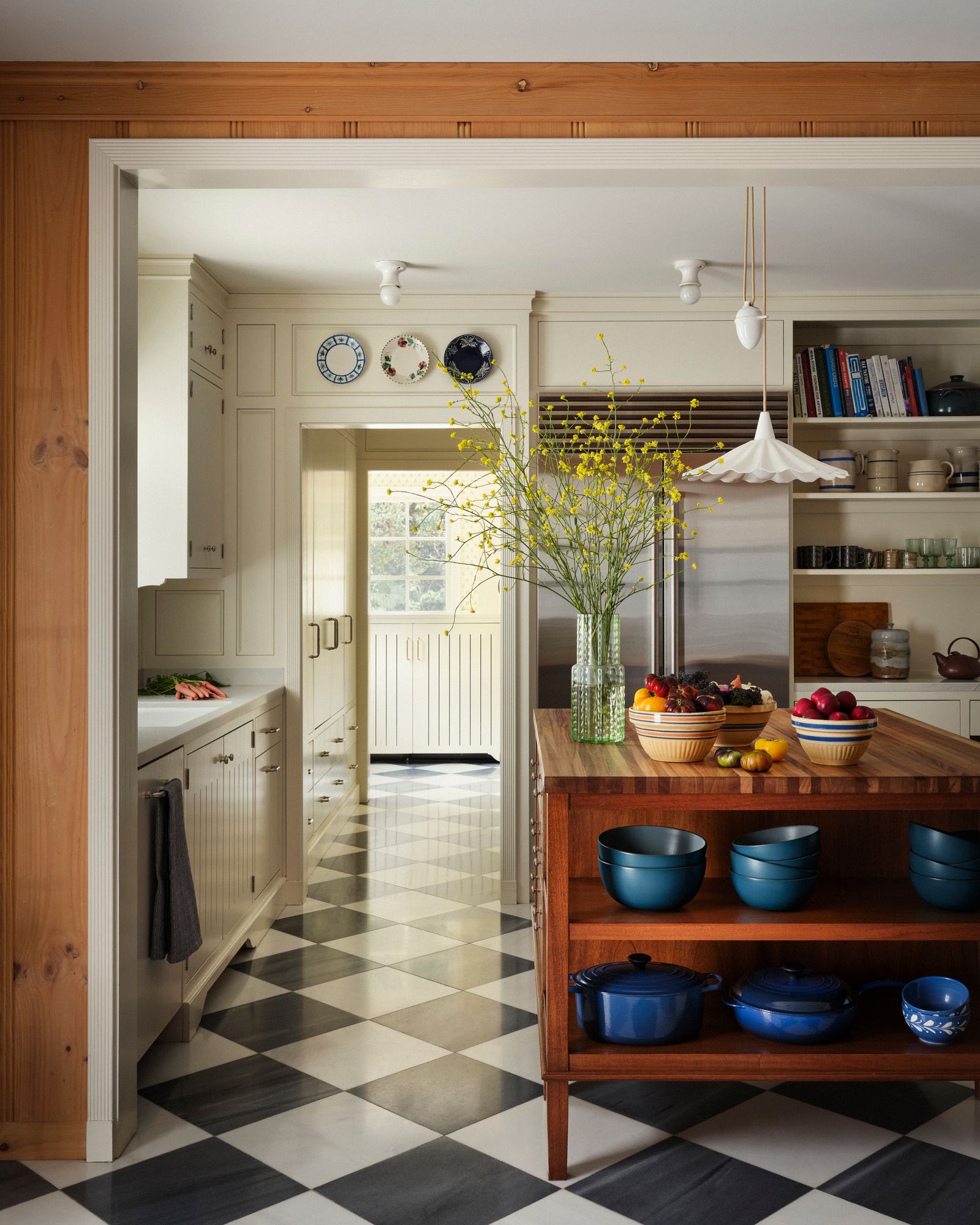 cucina color crema pavimento a scacchiera isola in legno stoviglie blu mensole boiserie