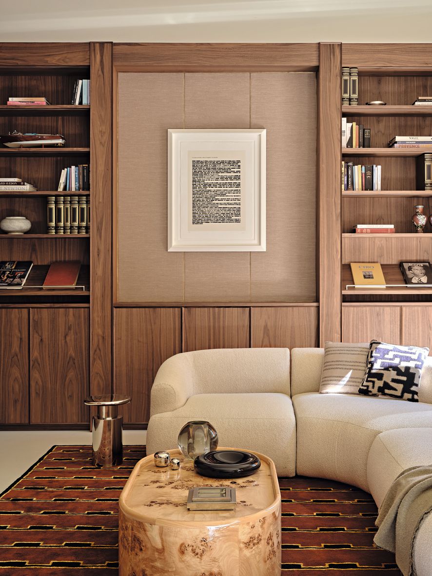 Divano beige coffe table in marmo tappeto libreria in legno libri opera d'arte alla parete appartamento milano