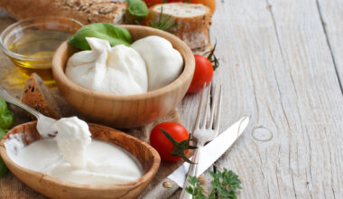 Una ciotola di burrata e una di stracciatella, accanto ad ingredienti della cucina italiana