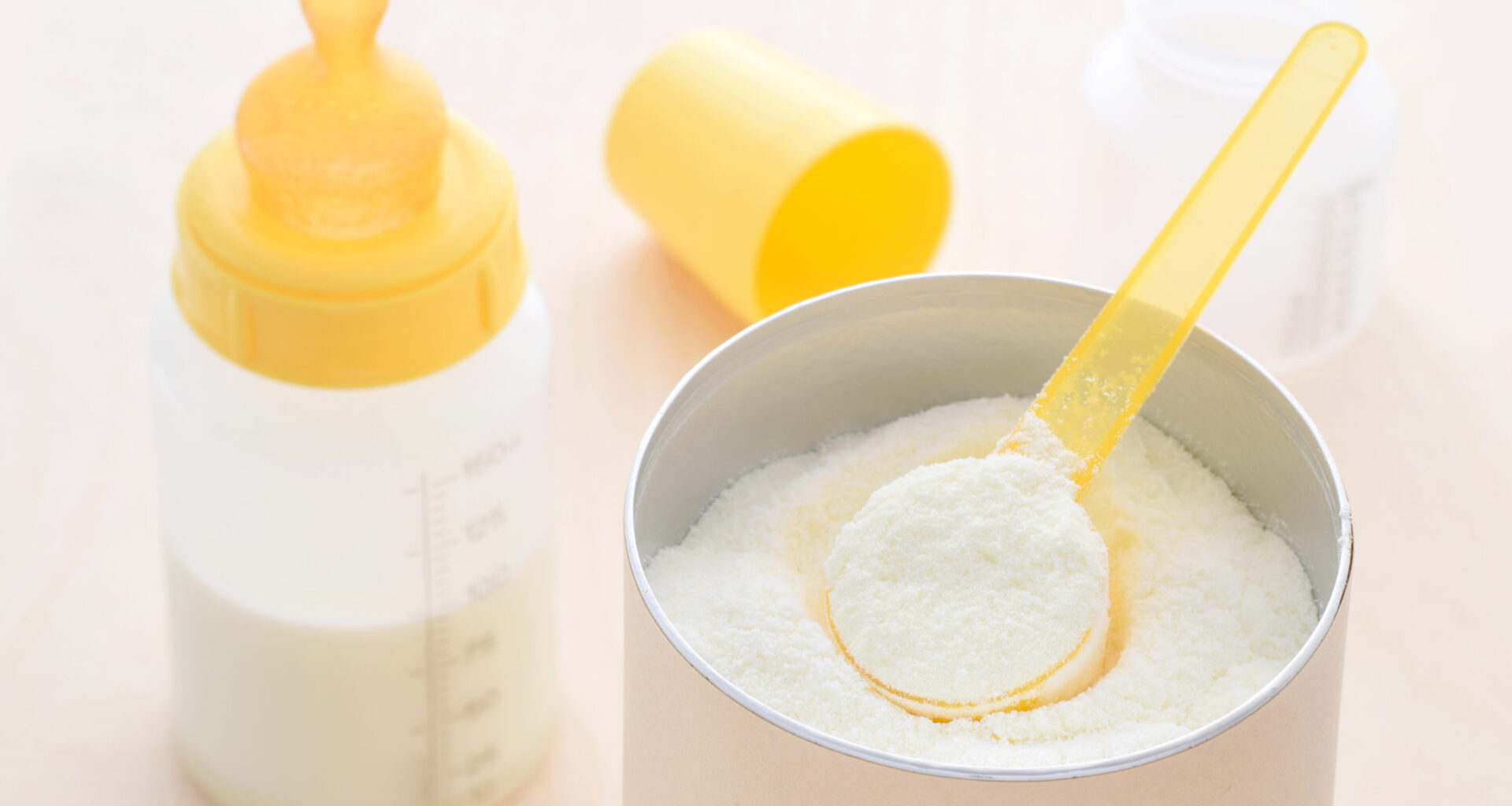 Barattolo di latte in polvere, accanto a biberon con misurino; concept: latte di crescita