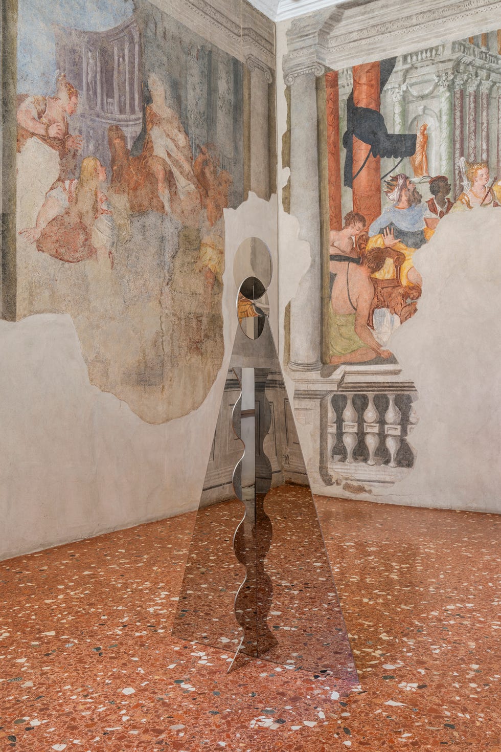 abstract sculpture set against an artistic wall mural in a historic room