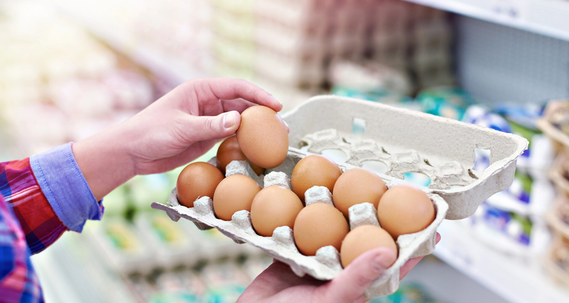 Una persona prende un uovo da un cartone da 12 uova nelle corsie di un supermercato