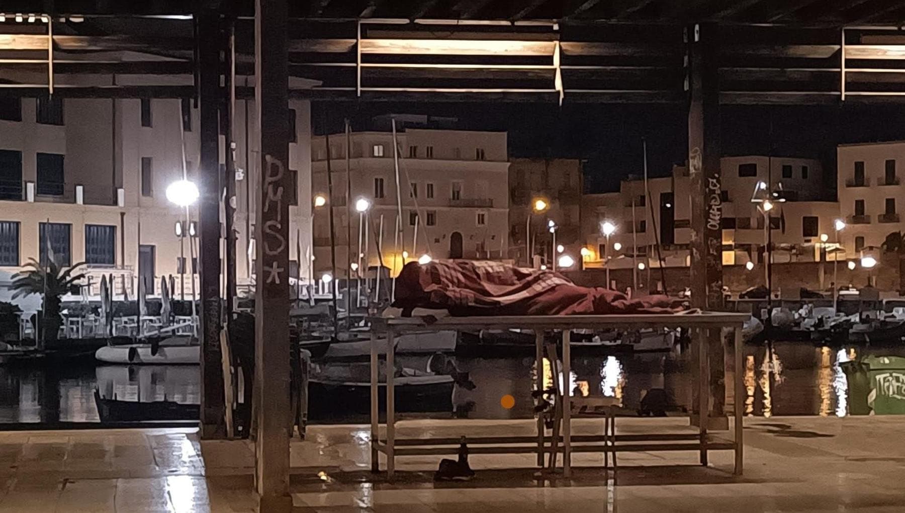 Un senzatetto dorme sulla bancarella del pesce, la foto che racconta l’altro lato del Natale a Bari