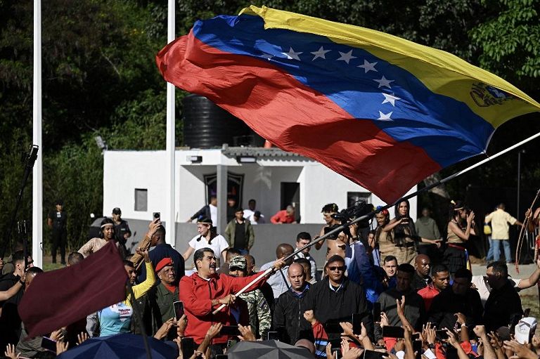Il presidente venezuelano Nicolás Maduro sventola una bandiera venezuelana durante una marcia per commemorare la "Giornata della Resistenza Indigena" a Caracas, il 12 ottobre 2025.