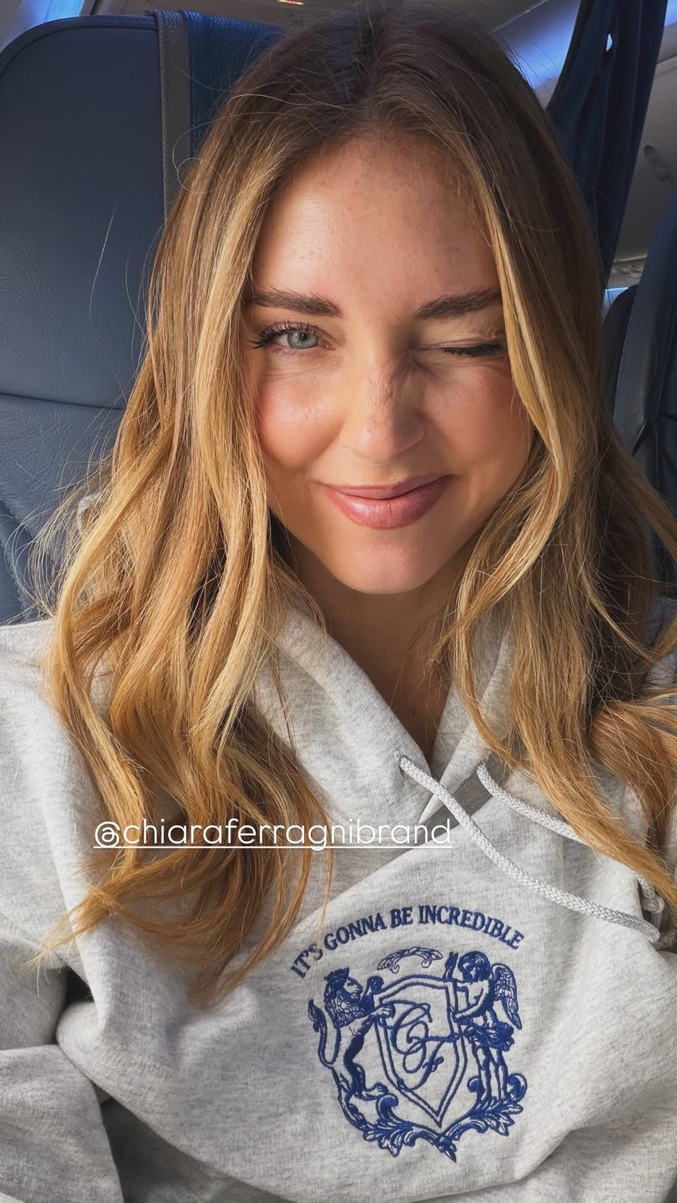 person wearing a grey hoodie with a logo