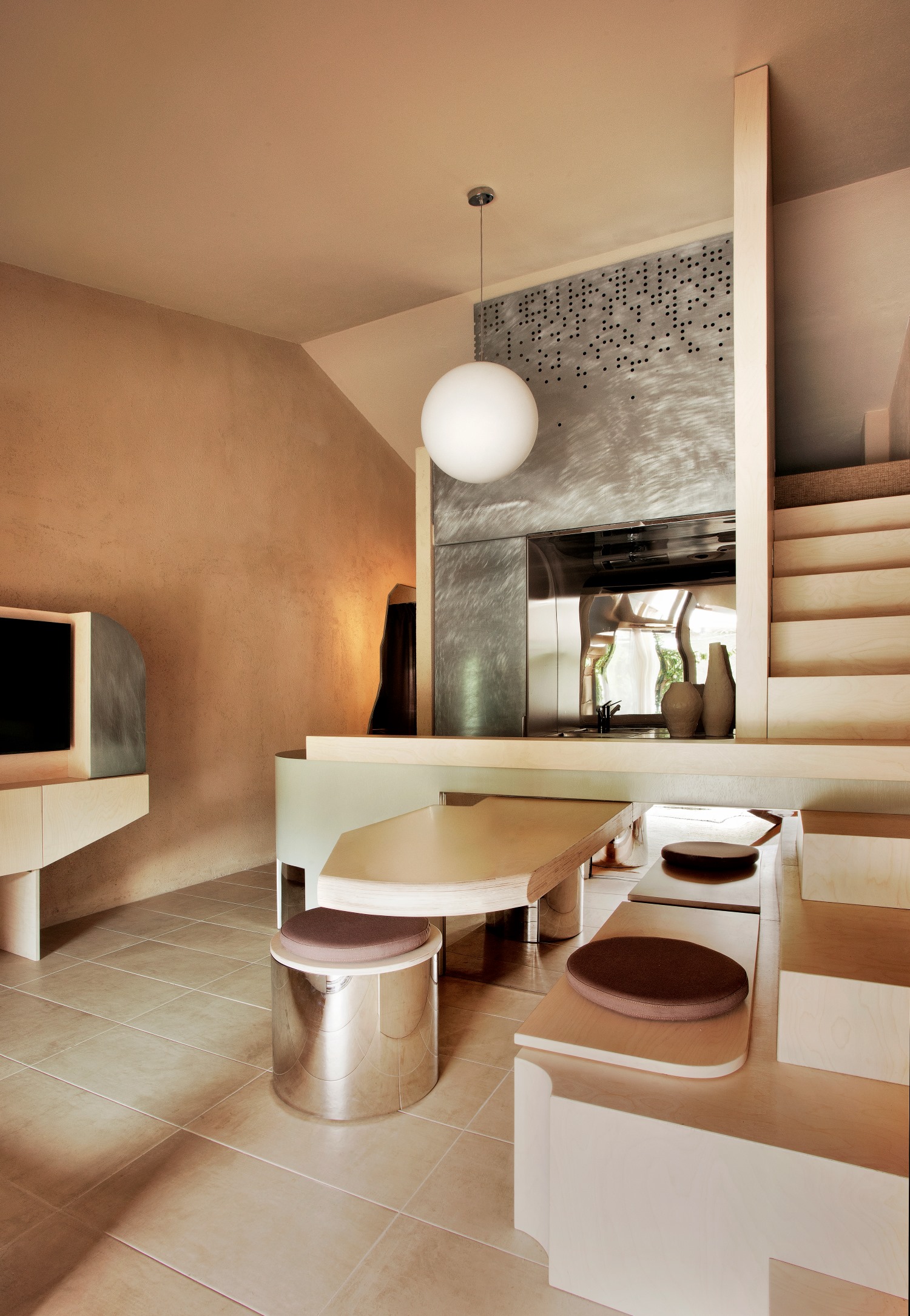 cucina sui toni del beige, lampadario rotondo bianco, pensili in acciaio e tavolo a sbalzo