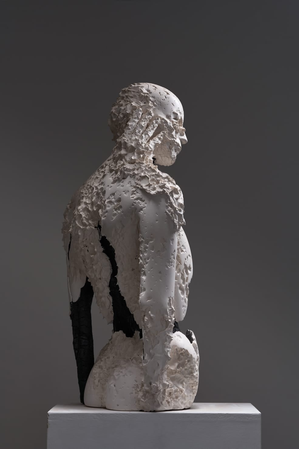 Aron Demetz è uno degli scultori italiani che hanno ridefinito, negli ultimi vent’anni, il rapporto tra figura umana e materia. Lavorando soprattutto sul legno – spesso bruciato, inciso, corroso – Demetz costruisce corpi attraversati da tensioni fisiche e simboliche, in cui la tradizione della scultura gardenese viene spinta oltre ogni dimensione decorativa. Le sue figure appaiono come presenze fragili e instabili, in bilico tra forma e disgregazione, tra identità e metamorfosi, dove la materia non è mai neutra ma parte attiva del processo espressivo. Nel 2025 questo percorso ha trovato nuove occasioni di confronto pubblico, tra cui la partecipazione alla mostra Damnatio figurae alla Fondazione Alberto Peruzzo di Padova, contesto che ha ribadito la centralità del suo lavoro nel dibattito contemporaneo sulla figura e sulla sua crisi.