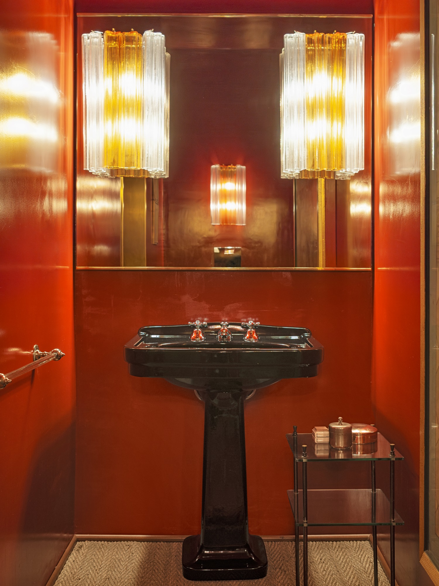 Nel bagno, sul lavabo di ceramica nera, specchio con applique Venini vintage, pareti rosse