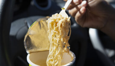 Impiegato che mangia noodles in auto durante l'ingorgo.
