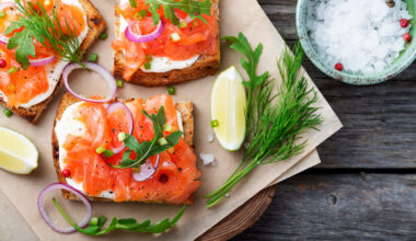 tartina salmone affumicato su tagliere con erbe aromatiche, lime e cipolla e ciotola di sale grosso